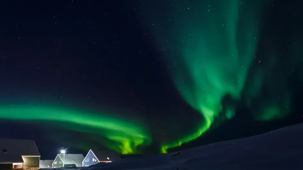 northern lights in a dark sky over houses